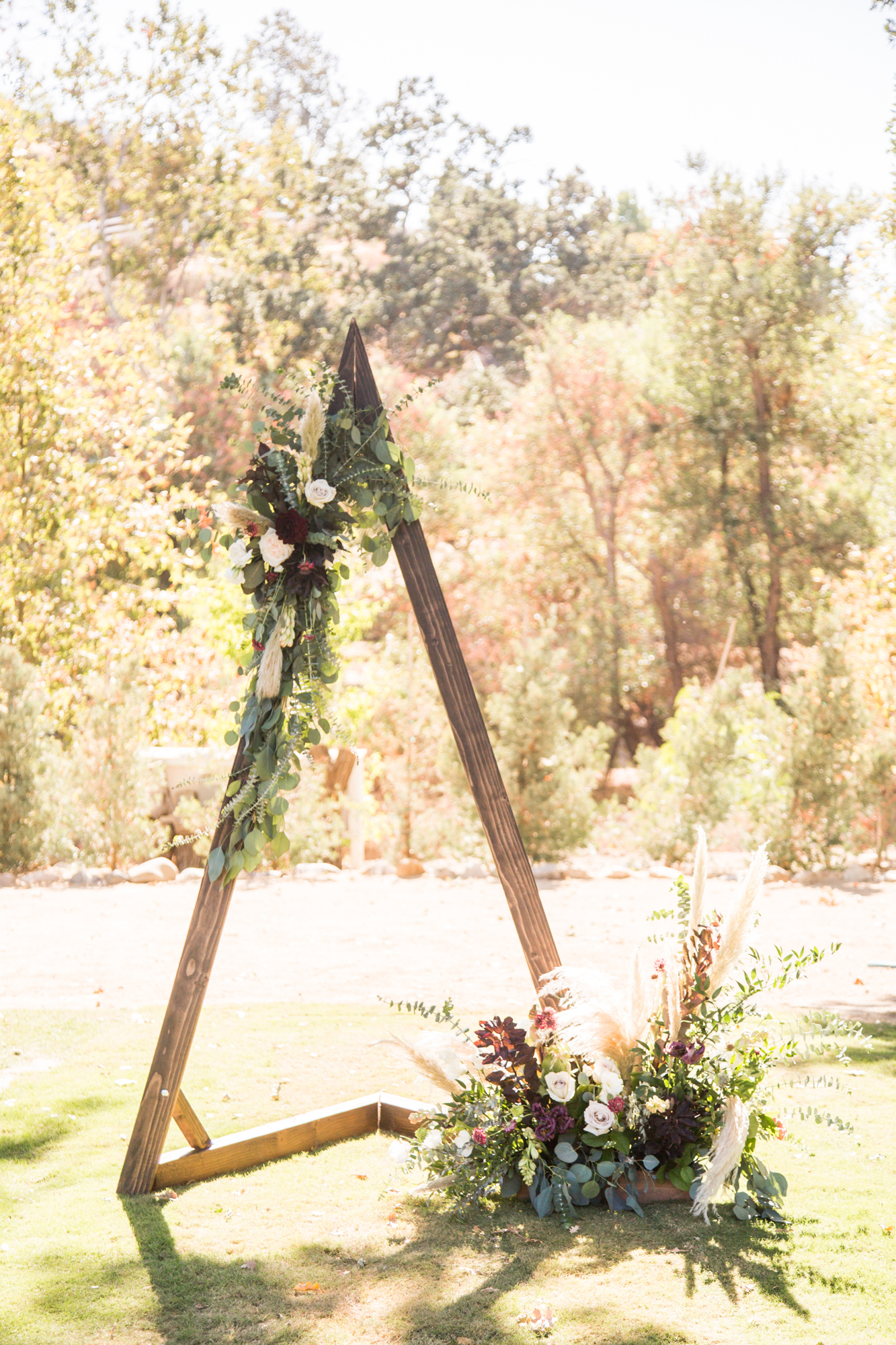 Wooden Triangle Arch adorned with moody florals